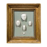 A set of five porcelain masks designed by August G&ouml;hring (1891 - 1965), mounted in carved and gilded Neoclassical frame, Nymphenburg, 20th century
