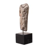 Neo-Assyrian statuette of a ruler, carved from a variety of alabaster, with his right arm bent and resting on the hilt of a dagger, 9th century B.C.