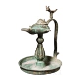 Bronze oil lamp on a disc-shaped base with floral and figurative decoration, Seljuk, 12th&ndash;13th centuries
