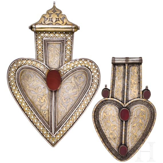 Two heart-shaped and partially gilt Turkmen silver and carnelian Teke "asyk" back-pendants, circa 1900