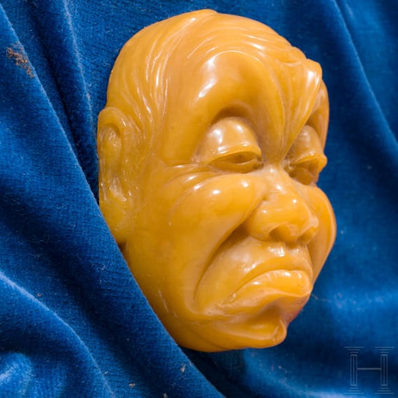 A framed amber carving showing two faces, Erbach/Hanau, 20th century