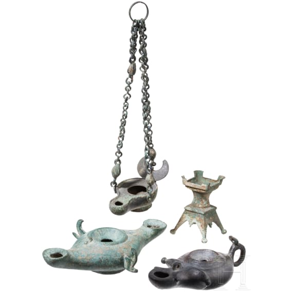 Three bronze oil lamps with hanging devices and a bronze candle holder, Roman and early Byzantine, 1st &ndash; 7th century A.D.