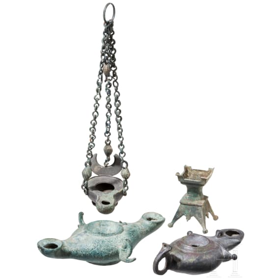 Three bronze oil lamps with hanging devices and a bronze candle holder, Roman and early Byzantine, 1st &ndash; 7th century A.D.