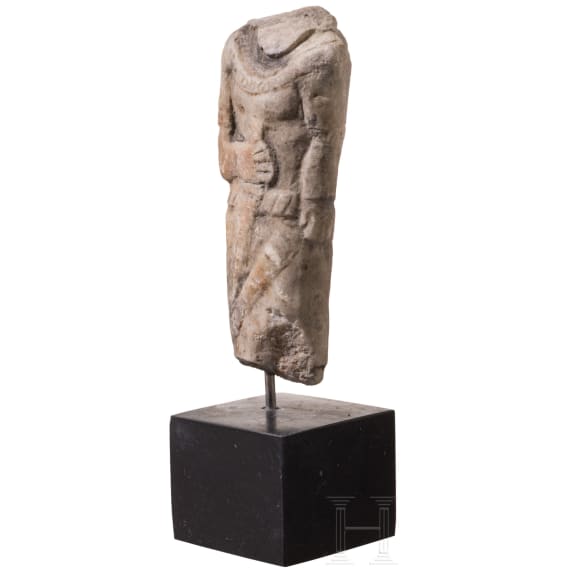 Neo-Assyrian statuette of a ruler, carved from a variety of alabaster, with his right arm bent and resting on the hilt of a dagger, 9th century B.C.