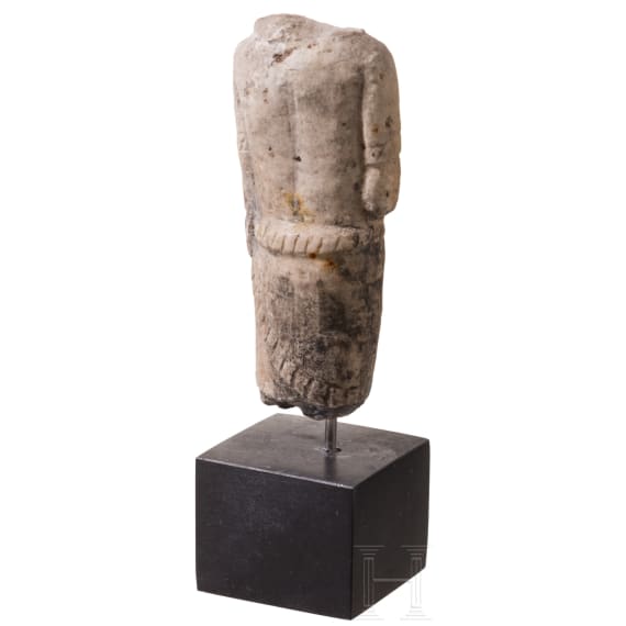 Neo-Assyrian statuette of a ruler, carved from a variety of alabaster, with his right arm bent and resting on the hilt of a dagger, 9th century B.C.
