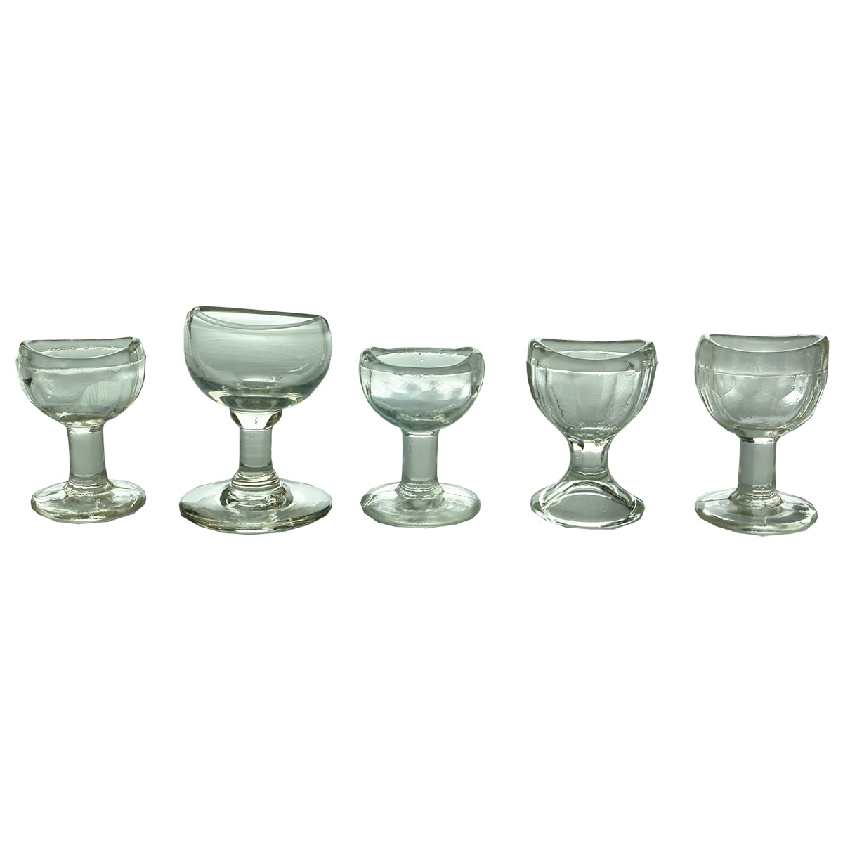 Five Clear glass Eye Baths. All Pedestal types with different bowls.