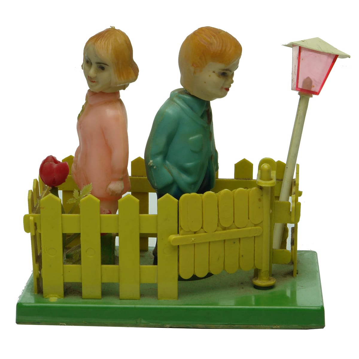 Toy. Plastic toy with boy and girl inside fence, gate opens to turn them around to kiss each other!