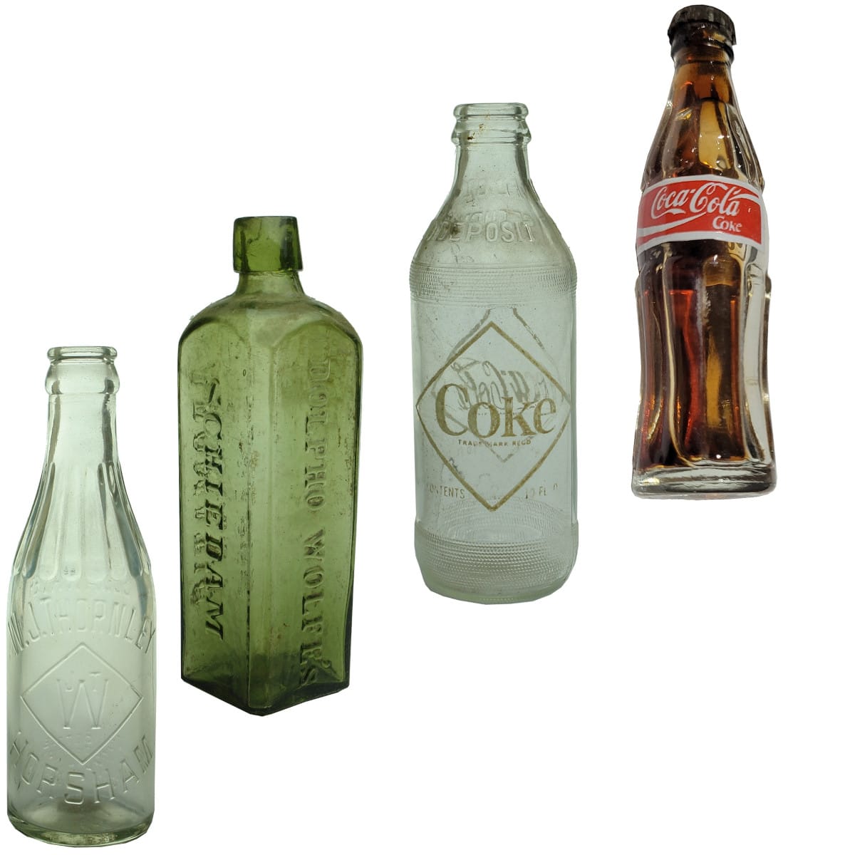 4 Bottles. 1. W. J. Thornley, Horsham, Soda Water. Crown Seal with Neck Pattern. Clear. 6 oz. 2. Udolpho Wolfe's Schnapps. Green. 13 oz. 3. Coca Cola Ceramic Label One Trippa. 10 oz. 4. Miniature Coca Cola Colombia.