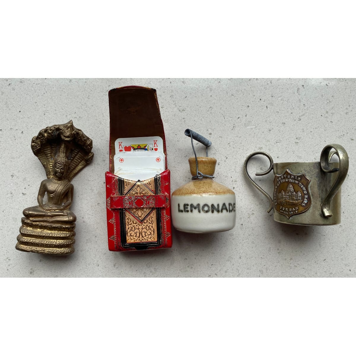 4 Souvenir pieces: Small brass figure of Buddha Metal cup opening of Durban Town Hall 1910 Tiny cards in leather case Tiny stoneware Lemonade jug.