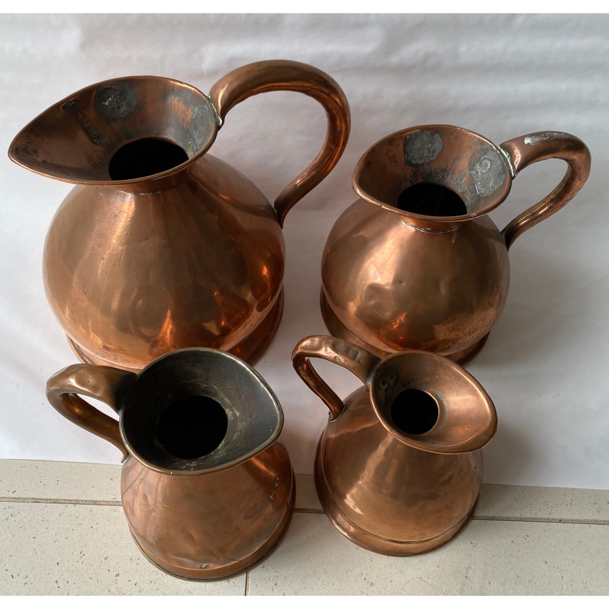 4 Copper Jugs. Pint to Gallon sizes. Makers stamps and sizes impressed.