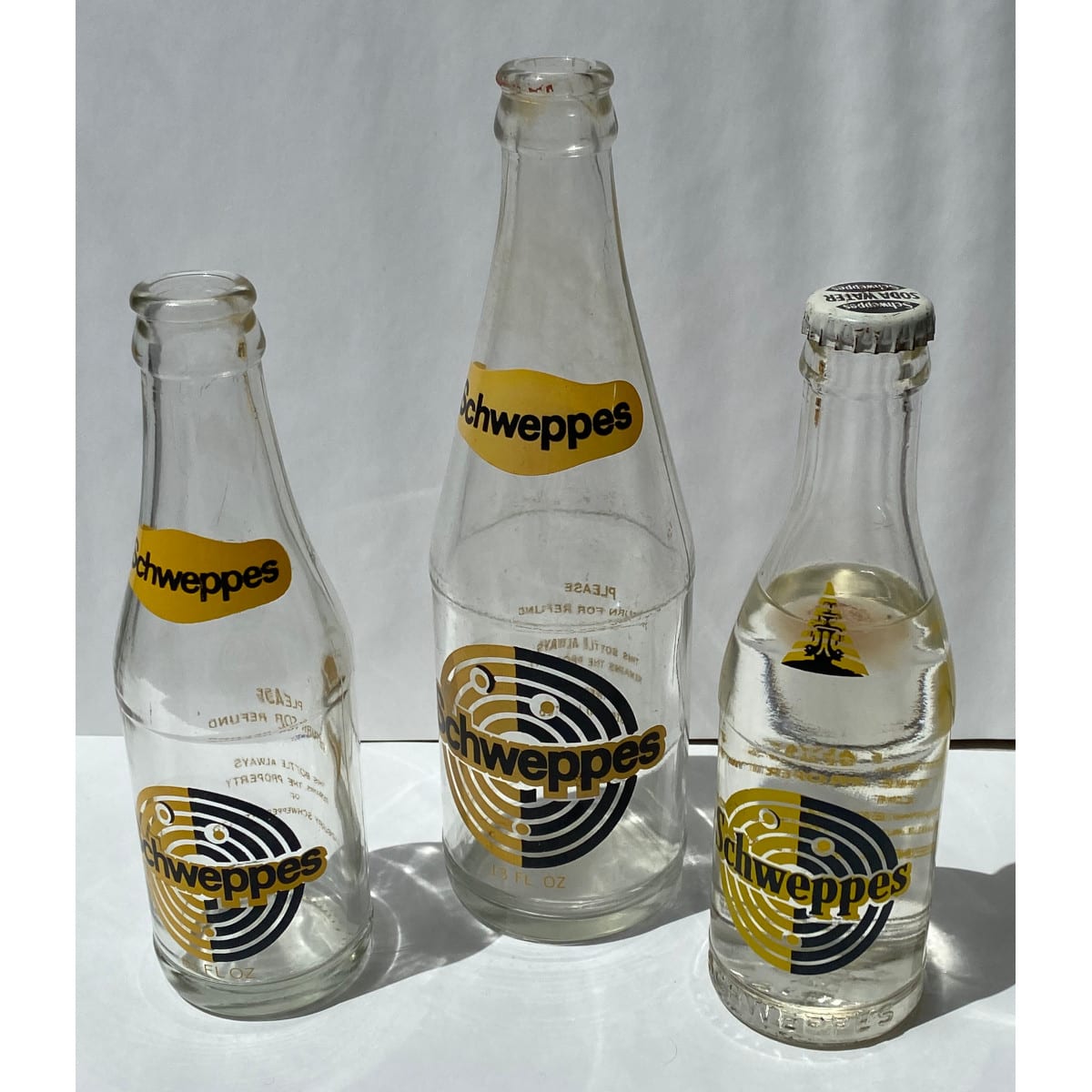 3 Ceramic Label Schweppes Bottles: 13 oz, 6.5 oz and 6.5 oz with original cap and contents.