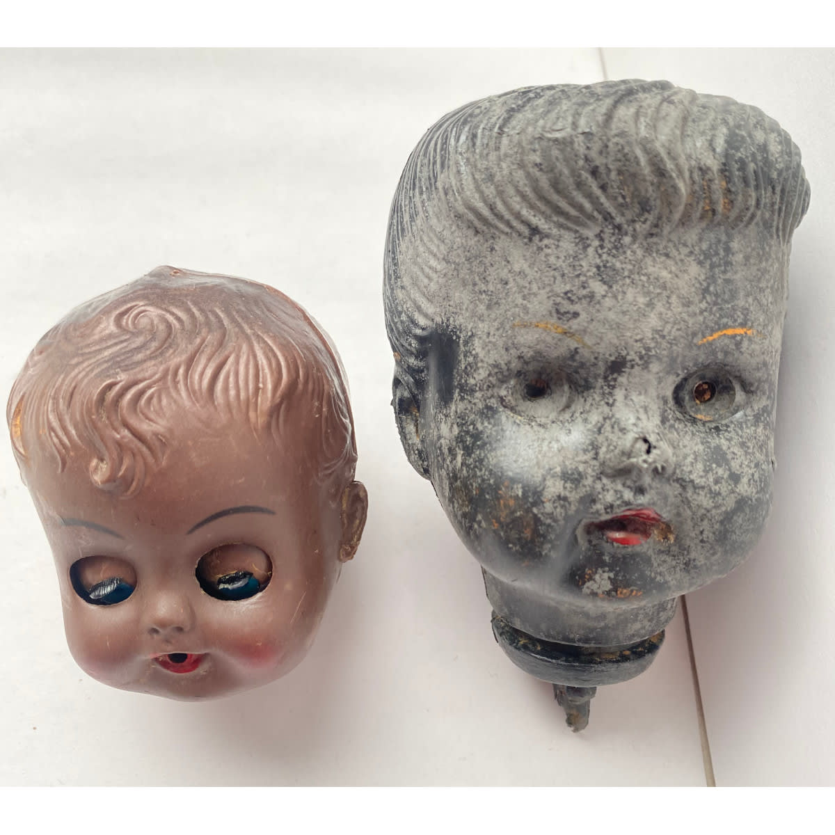 2 Plastic Dolls Heads. Large one without eyes, small one Made in Hong Kong and eys open and close as head is tilted.