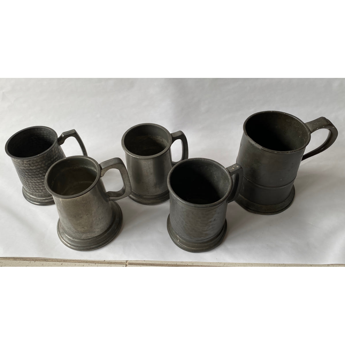 5 Pewter Mugs. Australian made one with glass base. Various English makers to the others. Pint & Half Pint sizes.