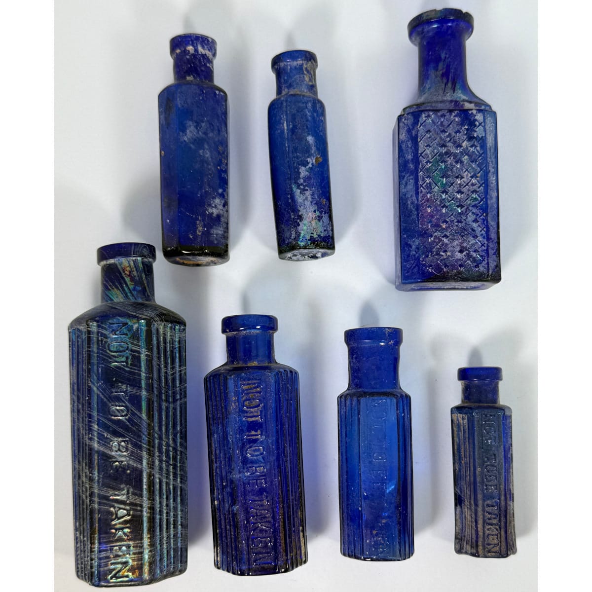 7 small blue poisons. 4 x Hexagonal Not to be taken, Made in Japan; Fancy oblong WT Co with diamond points; 2 plain Octagonal vials.
