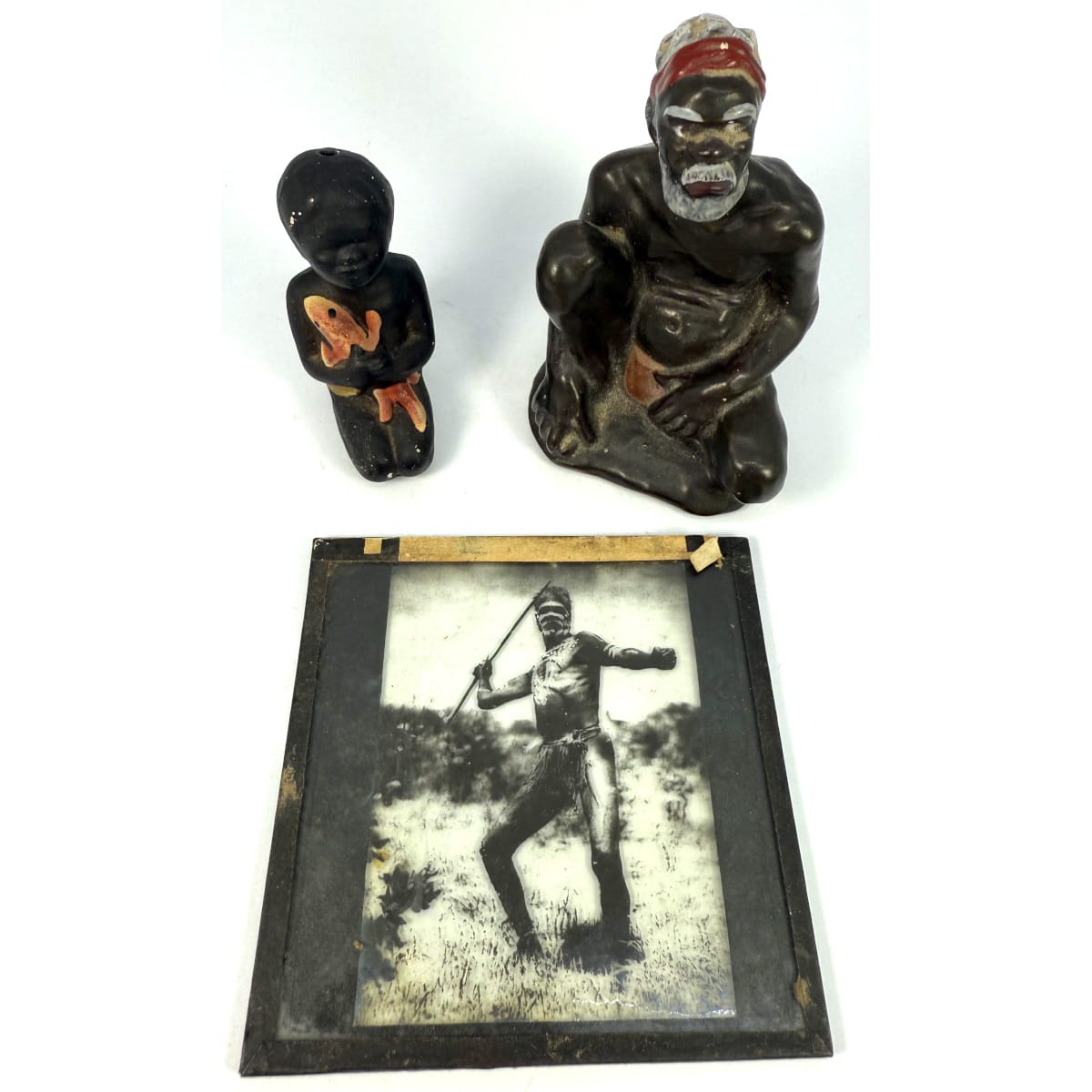 3 Aboriginal themed mid 20th Century pieces: Darbyshire Pottery figure of an Aboriginal Elder; Small ceramic Child holding a lizard; Movie theatre slide of Aboriginal man poised to throw a spear.