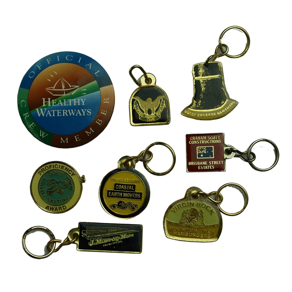 8 Items: 6 x enamel keyrings, 2 badges. Kelly Country Clothing; Virgin Rock; Graham Scott; Coastal Earthmovers; Healthy Waterways and more.