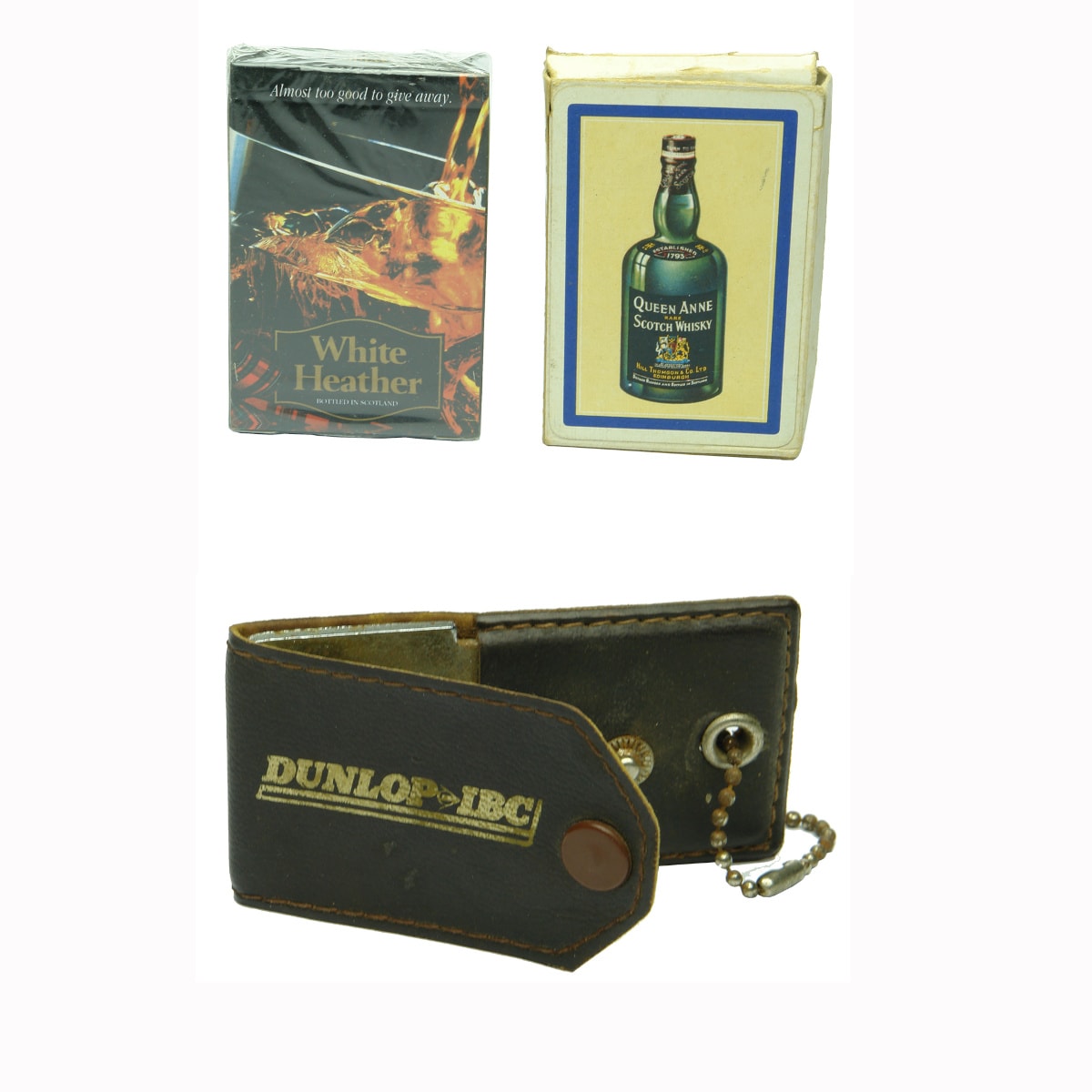 3 Items: 2 Decks of Promotional Playing Cards: Queen Anne Scotch Whisky, Compliments of Hill Thomson & Co; White Heather Scotch Whisky (still in plastic). Bottle Opener. Dunlop IBC. Keyring type with leather cover.