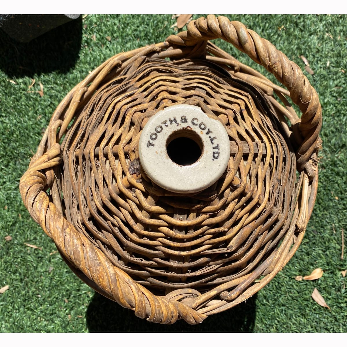 Demijohn. Lip printed Tooth & Coy Ltd. Wicker basket. (Sydney, New South Wales)