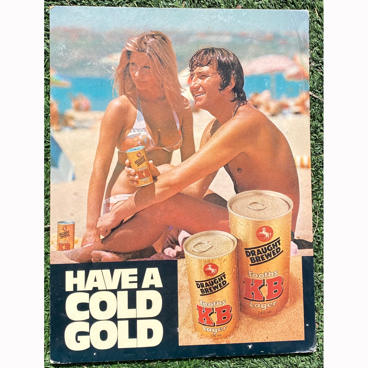 Cardboard Advertising Sign. Have a Cold Gold. Tooths KB Lager Cans. Beach Scene. (Sydney, New South Wales)