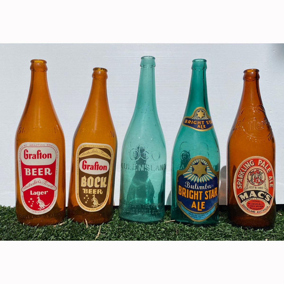 5 Beer Bottles: 2 BEB, one with Bulimba Bright Star Ale labels; 2 x different labelled Grafton Beers; Macs cider bottle with an unrelated Macs Pale Ale Rockhampton label. All labels are new old stock added to these bottles in modern times.