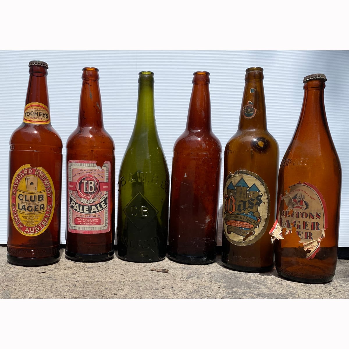 6 Beer Bottles. 4 Labelled. CB & WB Newcastle; Plain NSW Bottle Co; Tooths TB Ale; Tooheys Club Lager; Bass Australian Light Ale Canberra; Briton's Lager Beer.