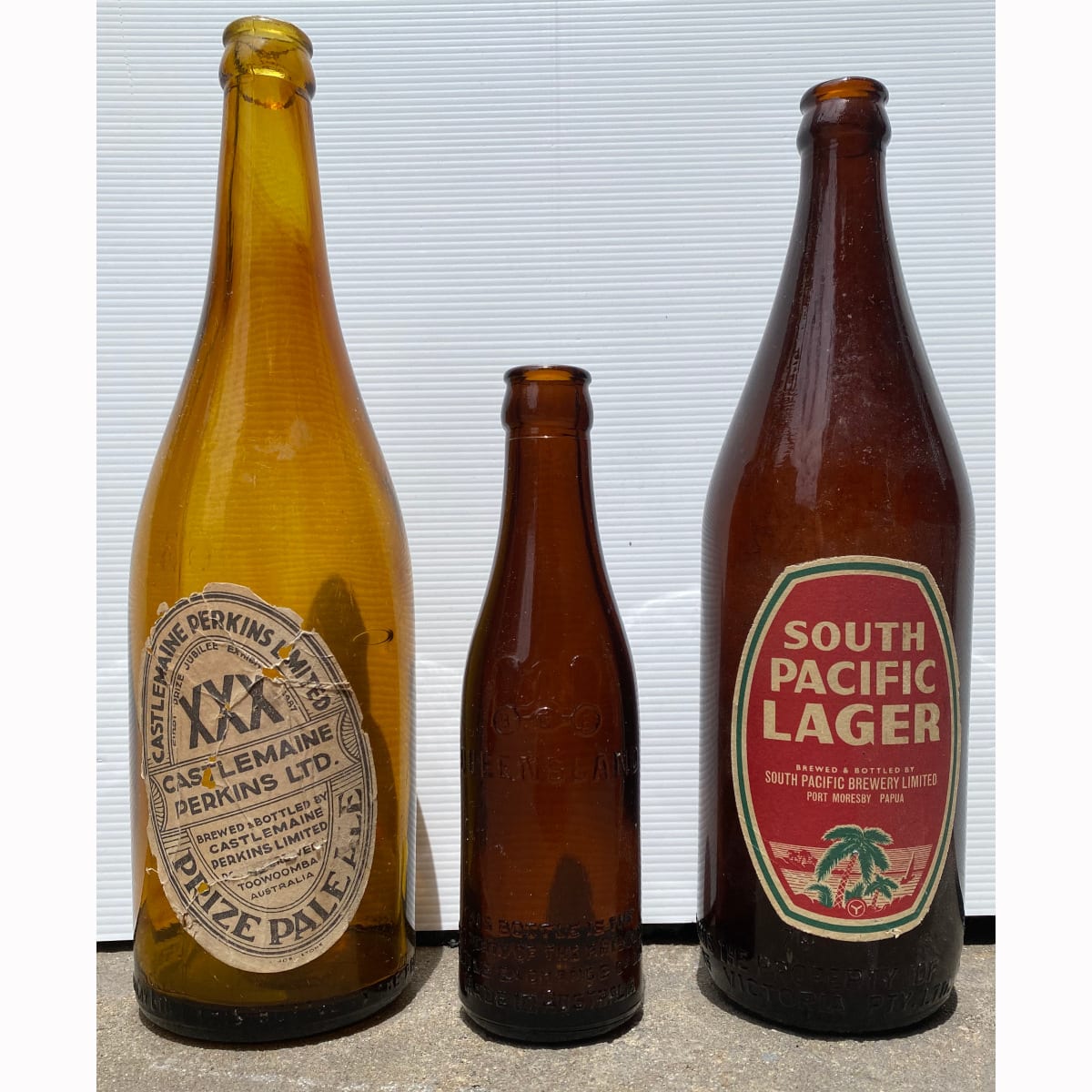 3 Beer Bottles: BEB crown seal with Castlemaine Perkins Toowoomba label; MBCV with South Pacific Brewery Port Moresby Papua label; 6 oz BEB Brisbane Amber crown seal.