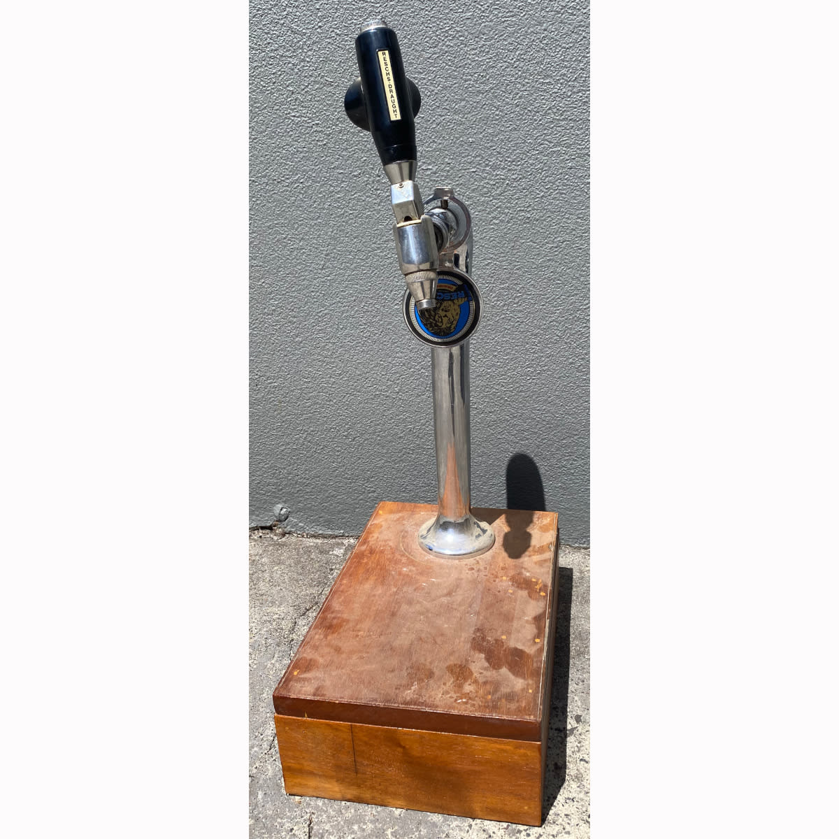 Beer tap mounted on a wooden stand. Two different Reschs Draught tap markers on it.