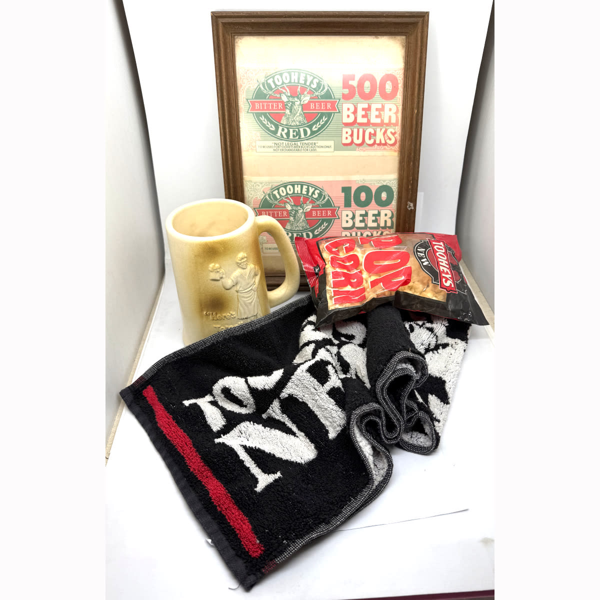4 Tooheys Promotional Items: Tooheys New bar towel; 2 x framed Tooheys Red "Beer Bucks" notes; Tooheys New Popcorn! (Expiry 1996!!); Moulded ceramic Here's To'ee beer mug. (New South Wales)