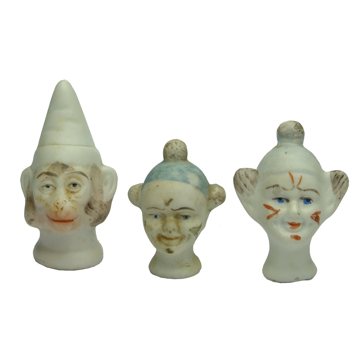 Dolls. Three unusual doll's heads: 1. Monkey with cone shaped cap. 2. Goblin looking character with blue cap. 3. Goblin looking character with light blue cap and red cheeks.