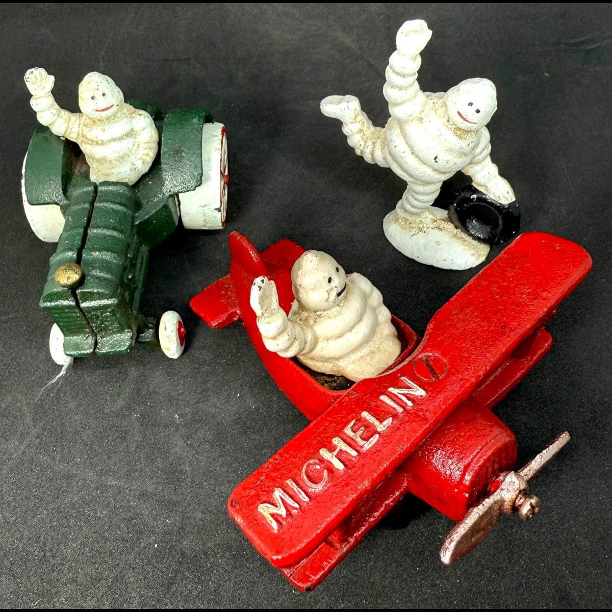 3 Reproduction Cast Iron figures. Michelin Man (Bibendum) in a Tractor, in a Biplane and rolling a tyre.