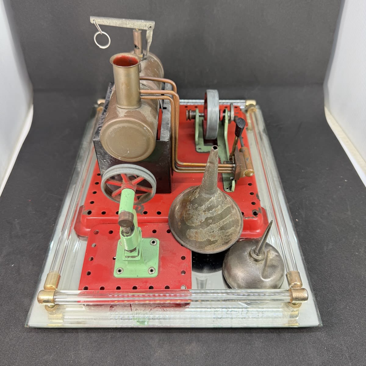 Model steam engine, oiler, funnel. MAMOD on the smaller stamper piece. On a mirrored serving tray.