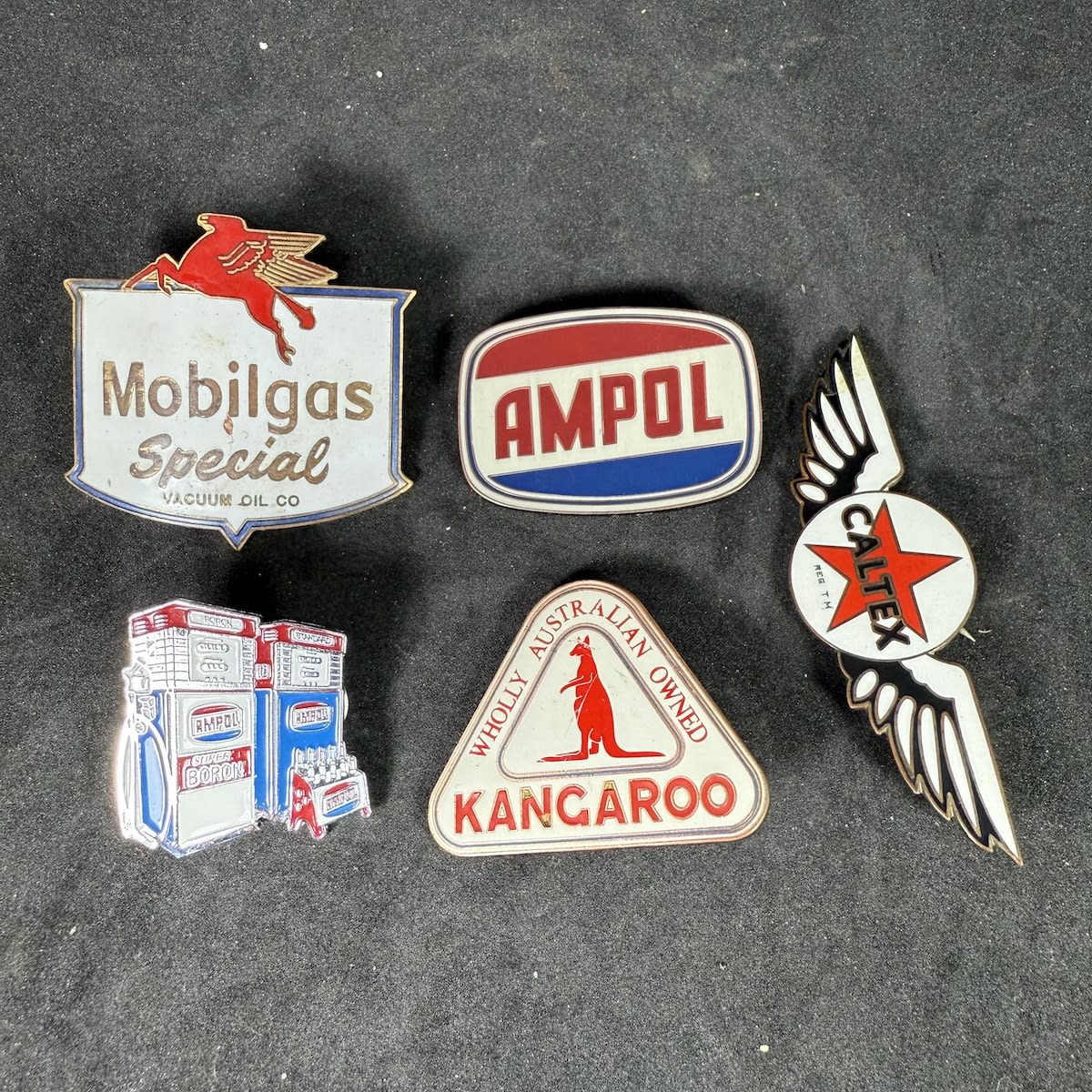 5 Enamel Badges promoting oil and petrol: Mobilgas Special; Ampol; Caltex with wings; 2 modern ones: Ampol with bowsers & oil rack; Kangaroo.