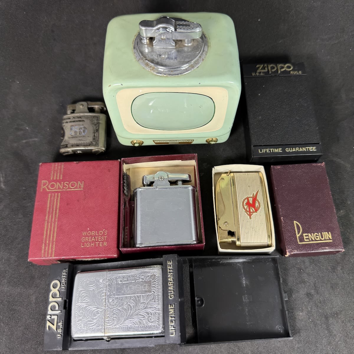 5 lighters and so forth. Old TV shaped; US $50 Note; Ronson in box and with small Ronson branded brushes; Empty Zippo box; Zippo lighter in box; Air India in Penguin box.