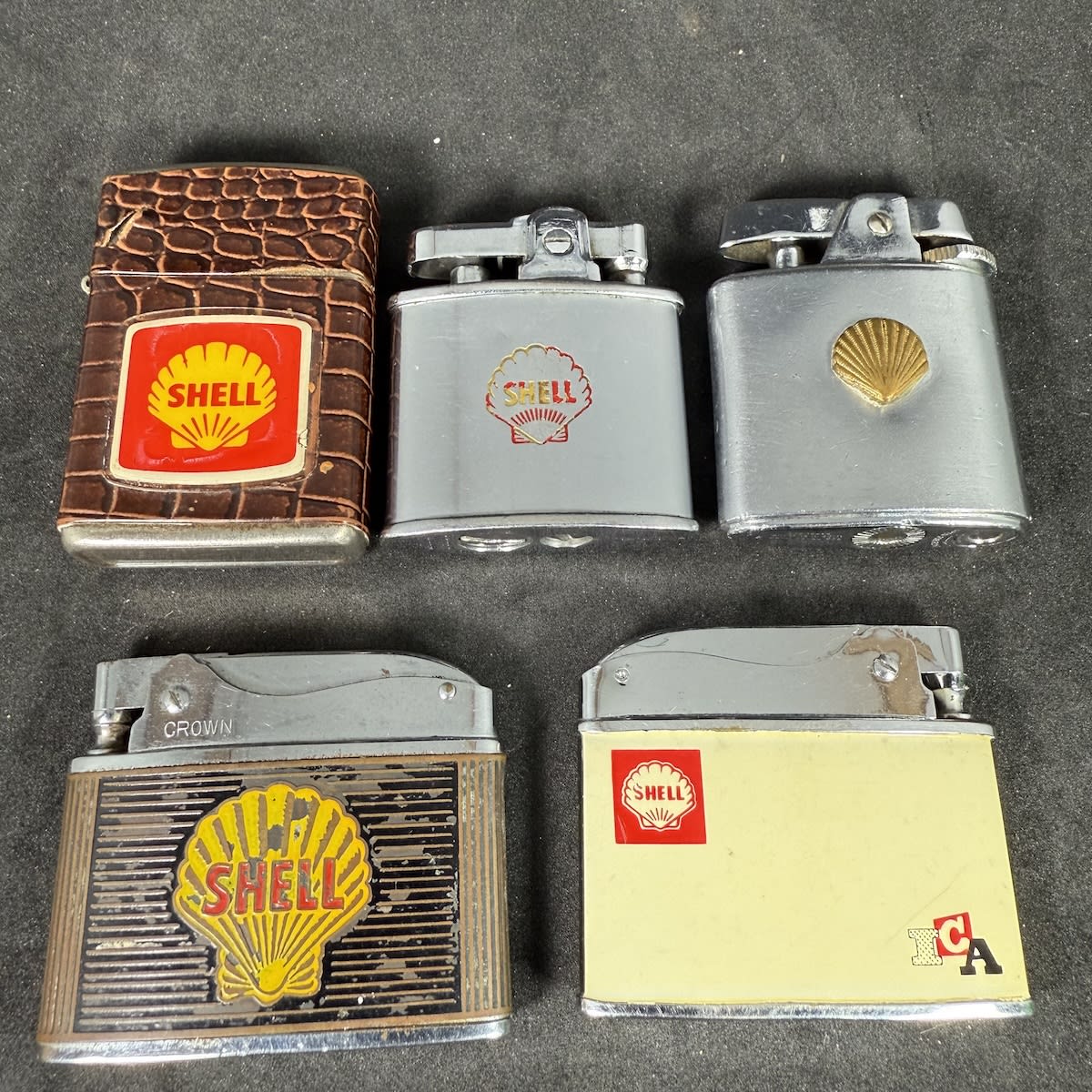 5 Shell promotional lighters: Crocodile skin type; Silver with map of the West Indies on the back; Brown with oil being poured on the back; Raised shell; Shell ICA, Mario Tabush, Elena.