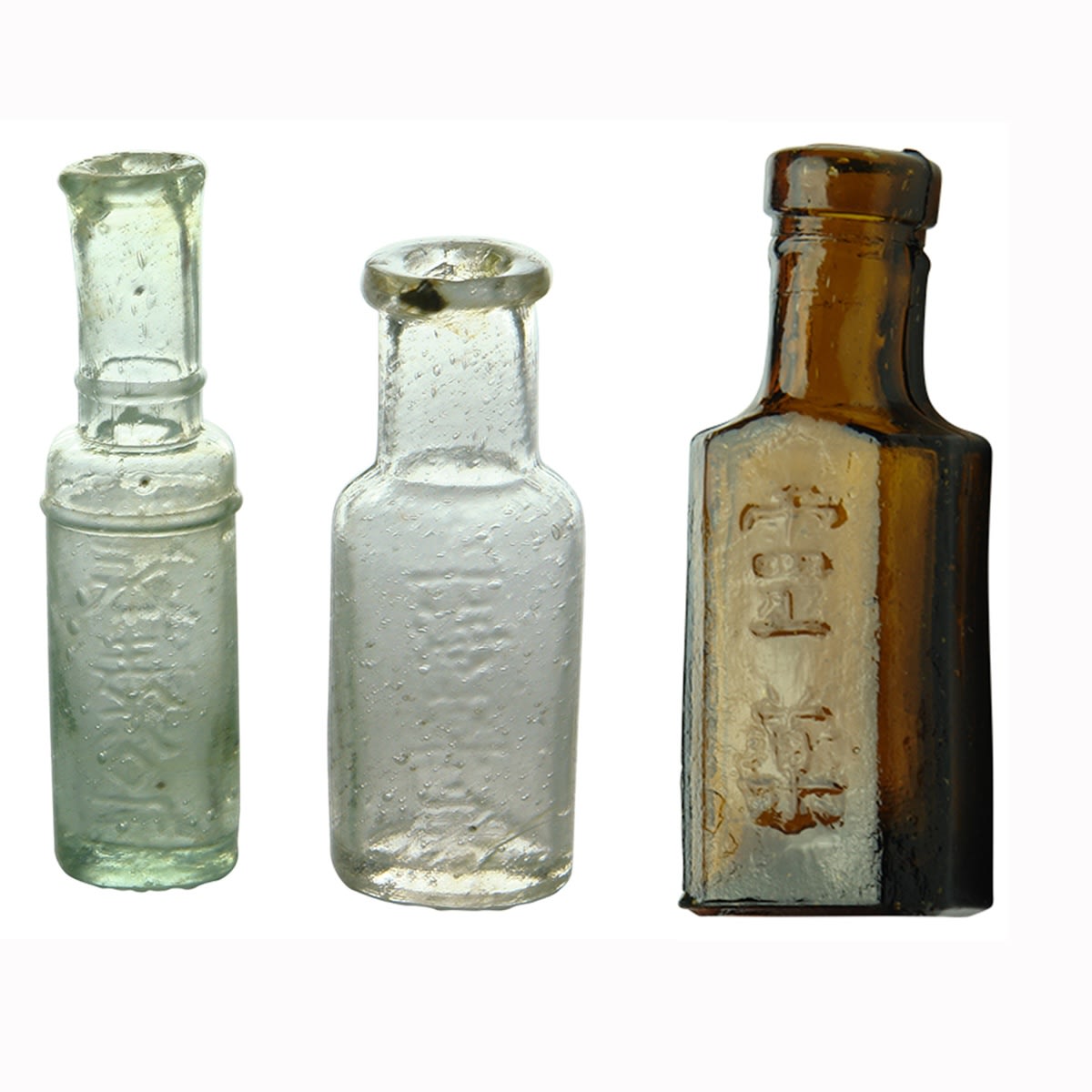 3 small Chinese/Japanese bottles: Pair of small clear/aqua medicine bottles with characters;  Small amber rectangle bottle with two characters to face.