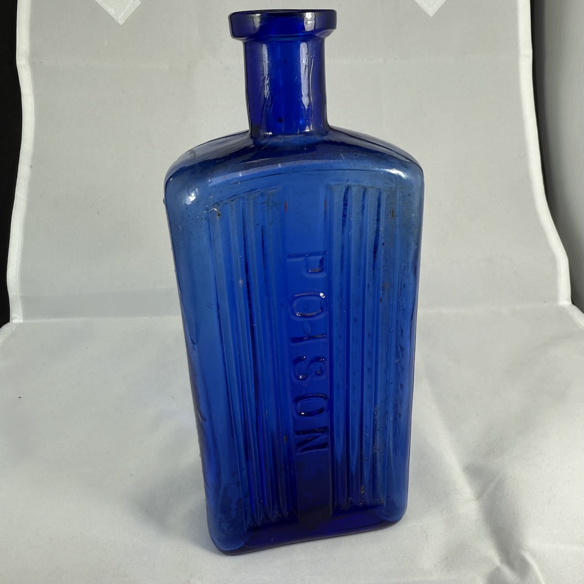 Poison. Poison down middle of front. 4 Deep grooves either side. 3 columns of crosses on sides. A base mark. 16 ozs. Oblong. Cobalt Blue. (South Australia)