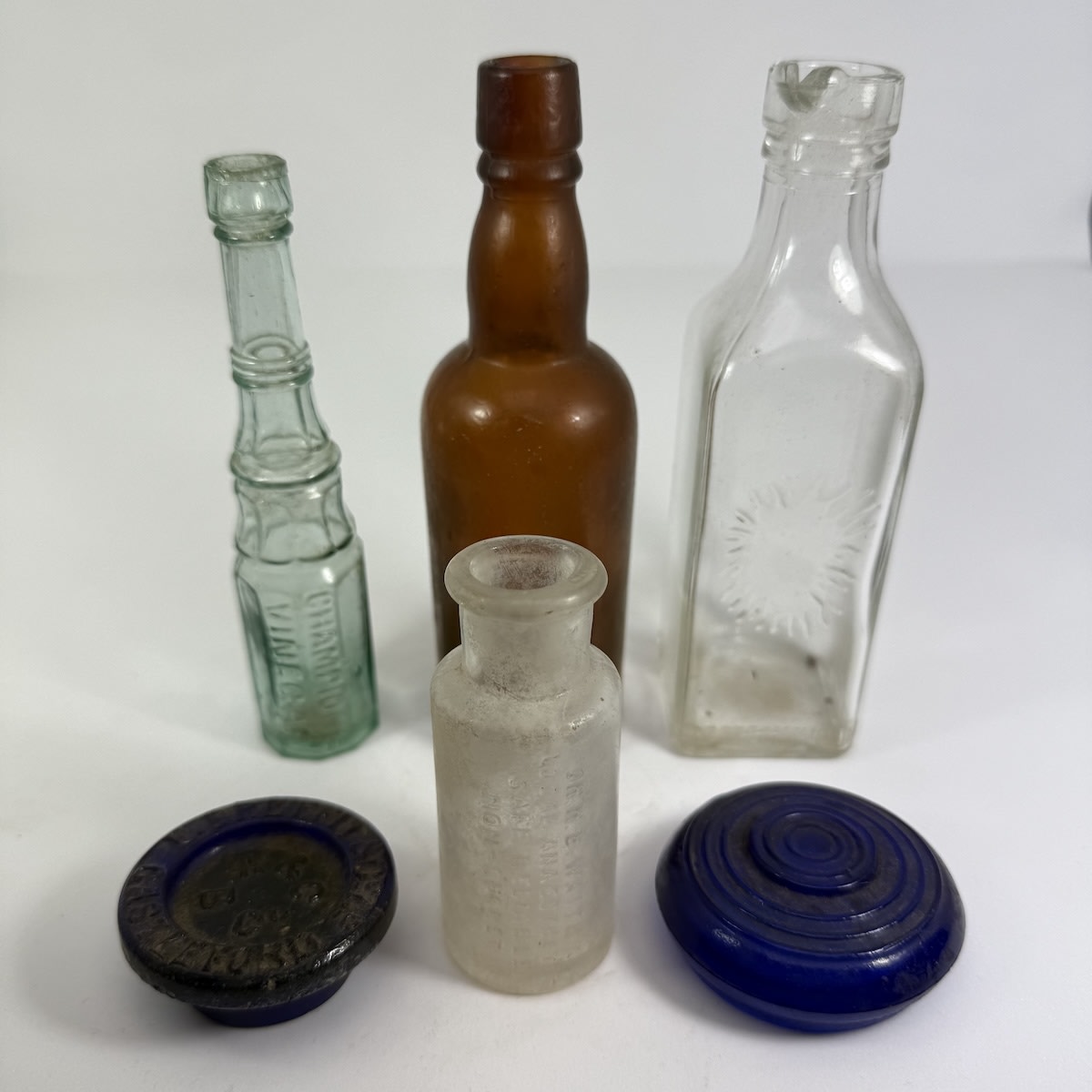 6 Small Bottles and stoppers: Stephens Ink; Mini Champions Vinegar; Plain Amber; Waite's Local Anaesthetic; Round blue lid. Breffit & Co Cobalt Blue Stopper.