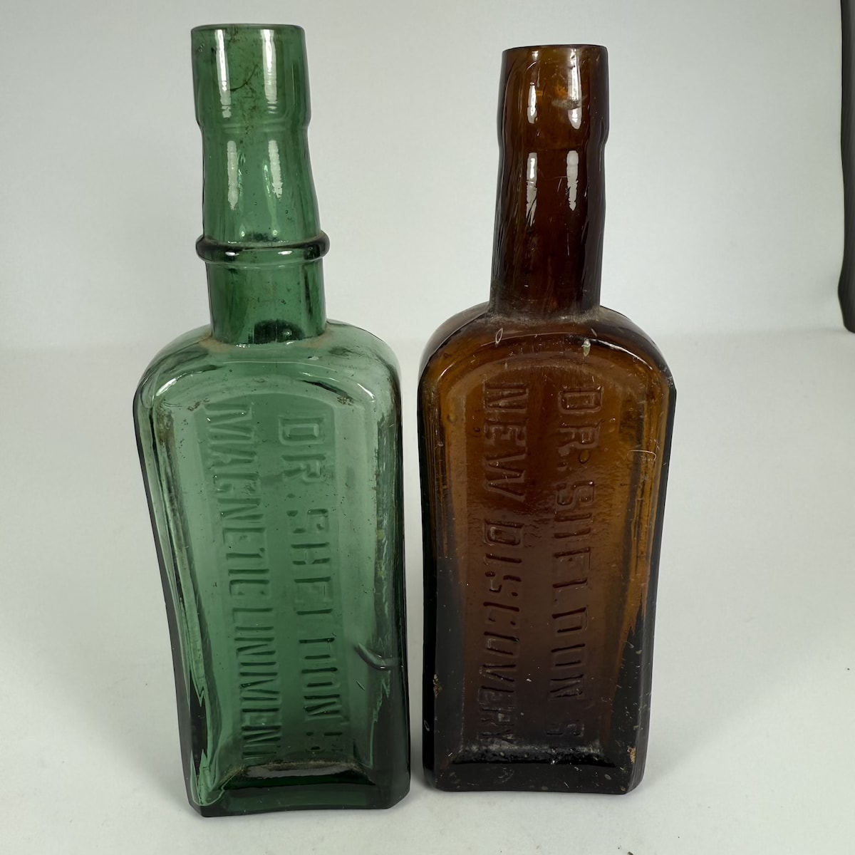 2 Dr Sheldon's Bottles: Dr Sheldons Magnetic Liniment (Green); Dr Sheldons New Discovery (Amber). Small size. 2 oz.