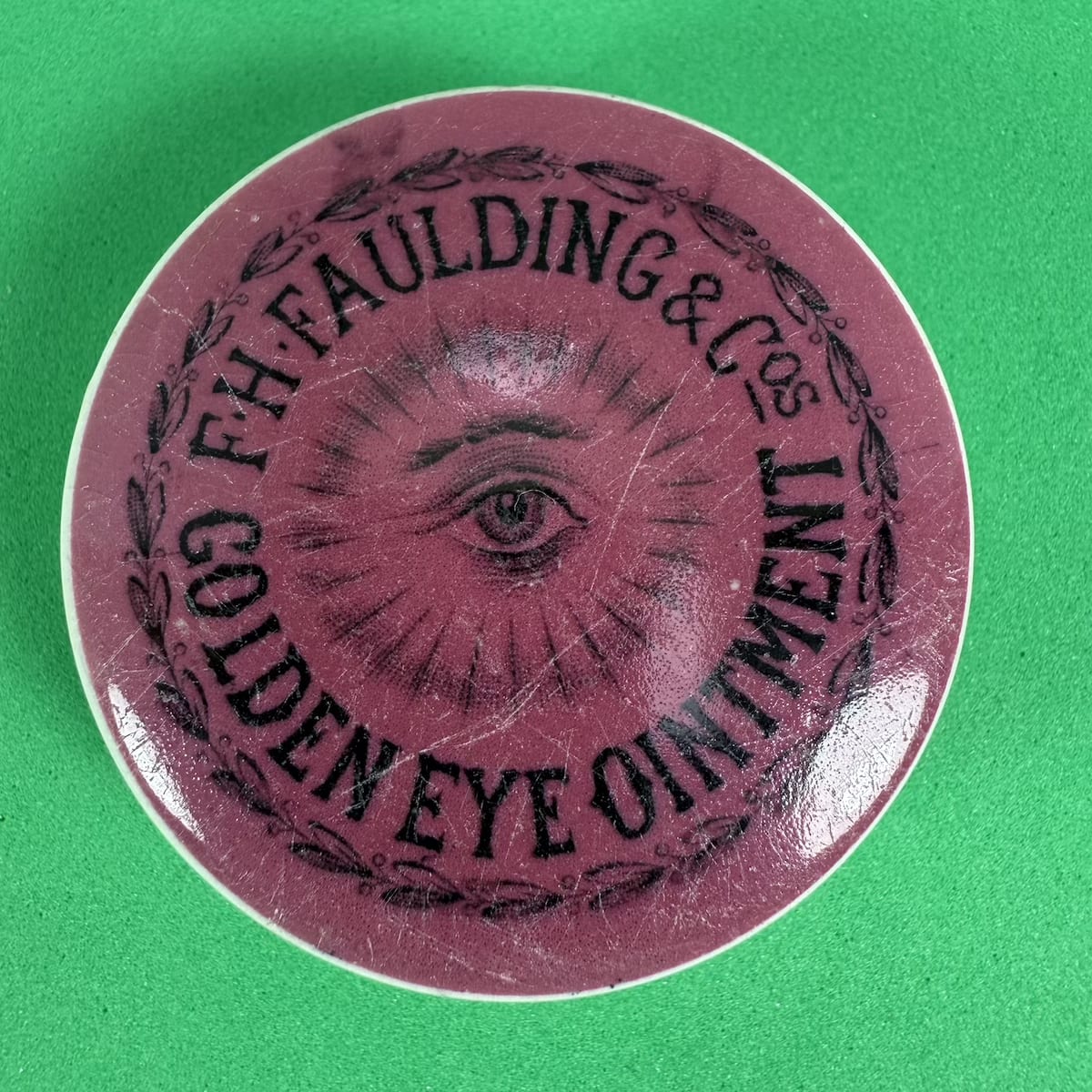 Pot Lid. F. H. Faulding & Cos, Golden Eye Ointment. Black on Pink. 50 mm diameter. (South Australia)