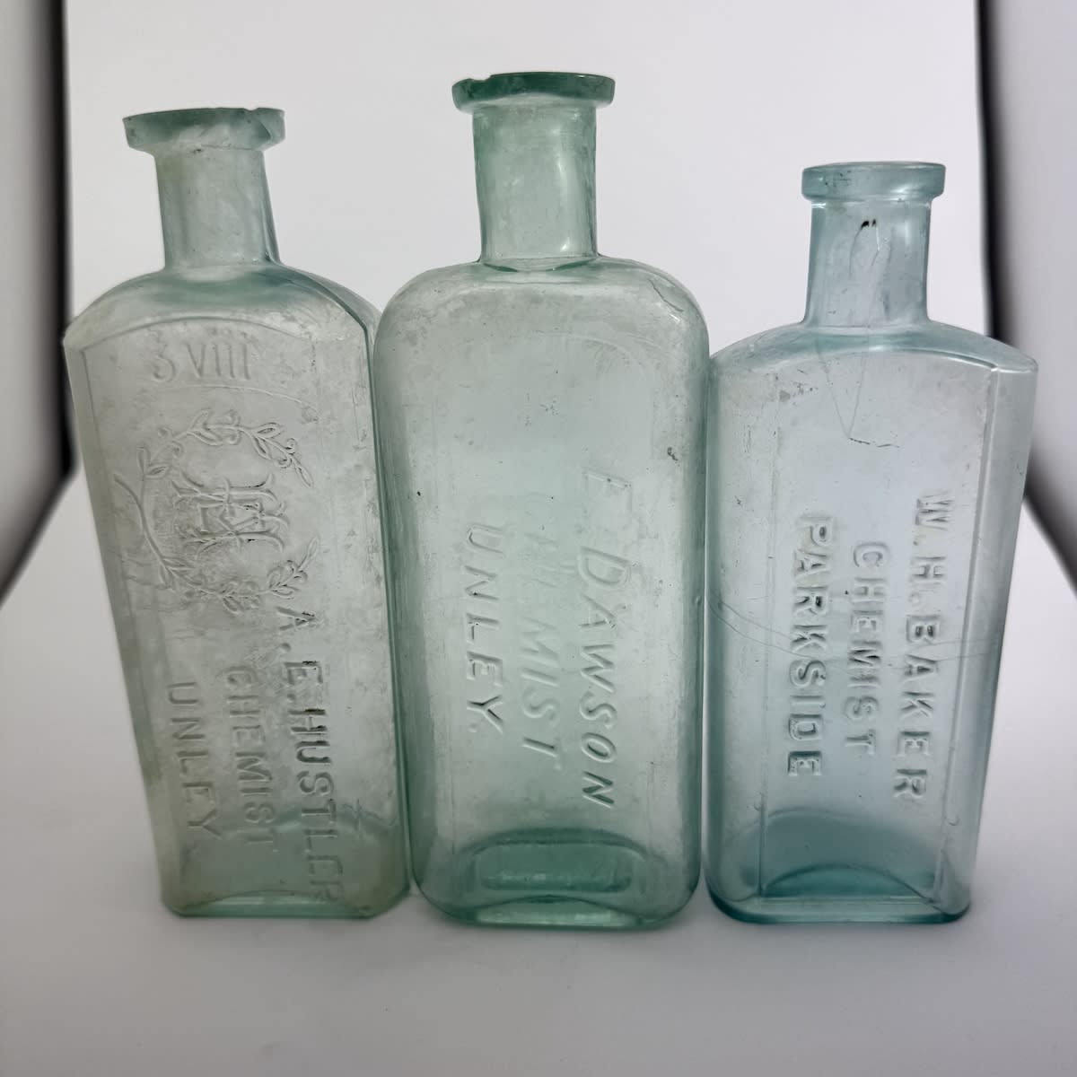 3 Chemist Bottles: A. E. Hustler, Unley. 8 oz. 168 mm. 2. E. Dawson, Unley. 8 oz. 169 mm. 3. W. H. Baker, Parkside. 6 oz. 155 mm. (South Australia)
