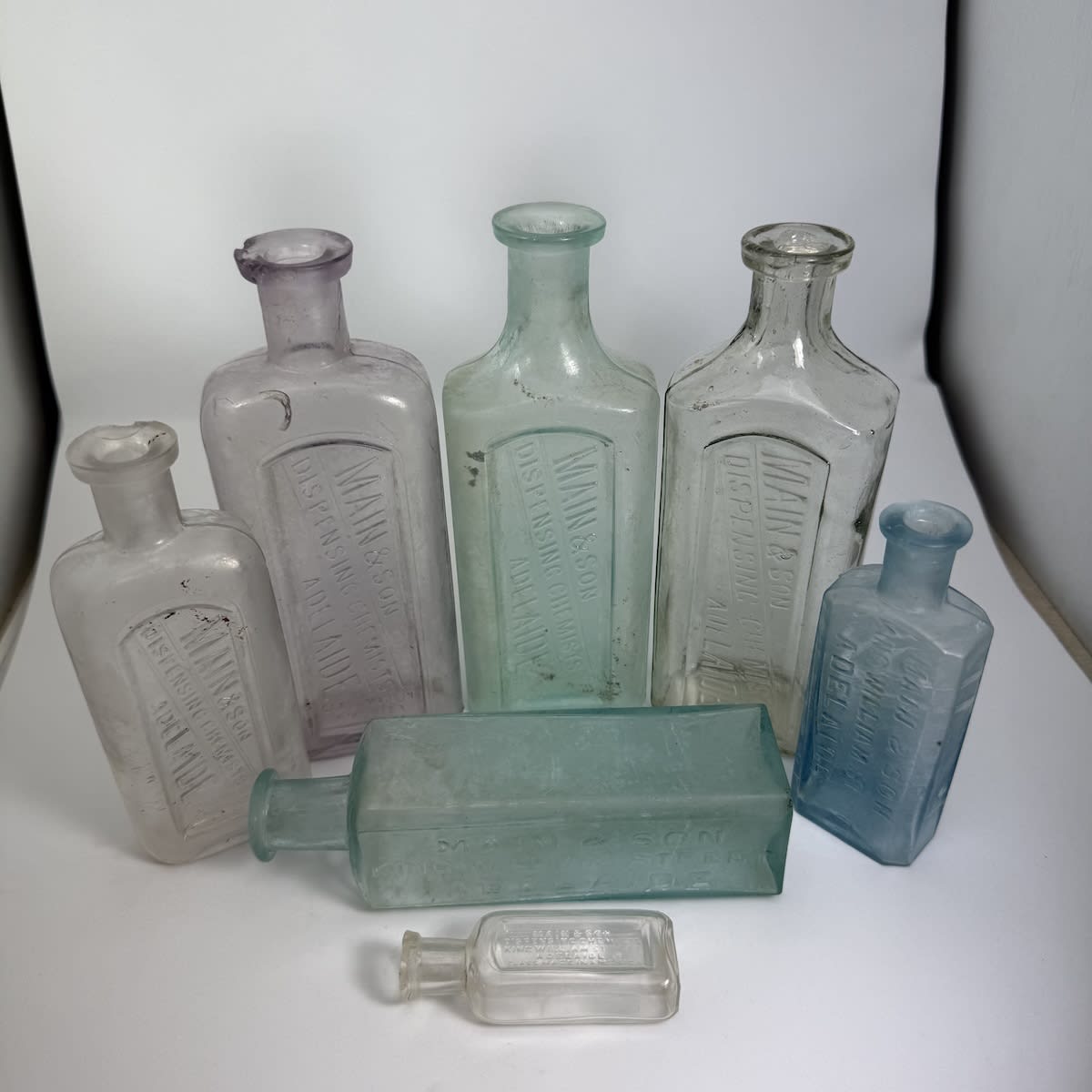 7 Main & Son Adelaide Chemist Bottles. King William Street. Various sizes and styles. (South Australia)