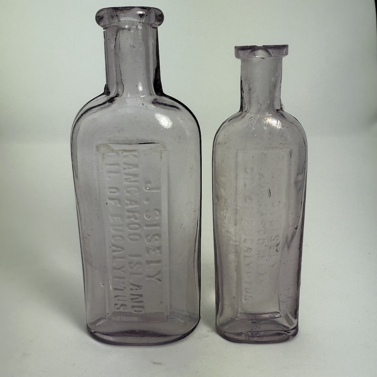 2 Eucalyptus Oil Bottles. Both: J. Sisely, Kangaroo Island. 2 & 1 oz. Sun Coloured Amethyst. 135 & 122 mm. (South Australia)