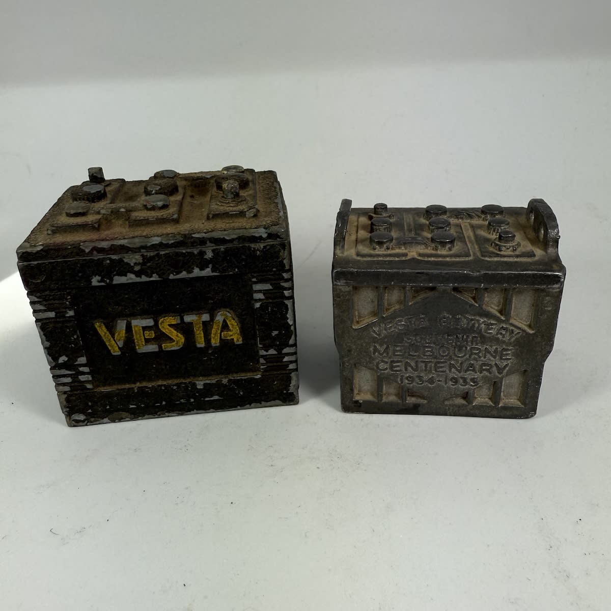 2 Metal Items: Lidded box in the shape of a Vesta battery and Small very heavy paperweight souvenir Vesta Battery Melbourne Centenary 1934-35.