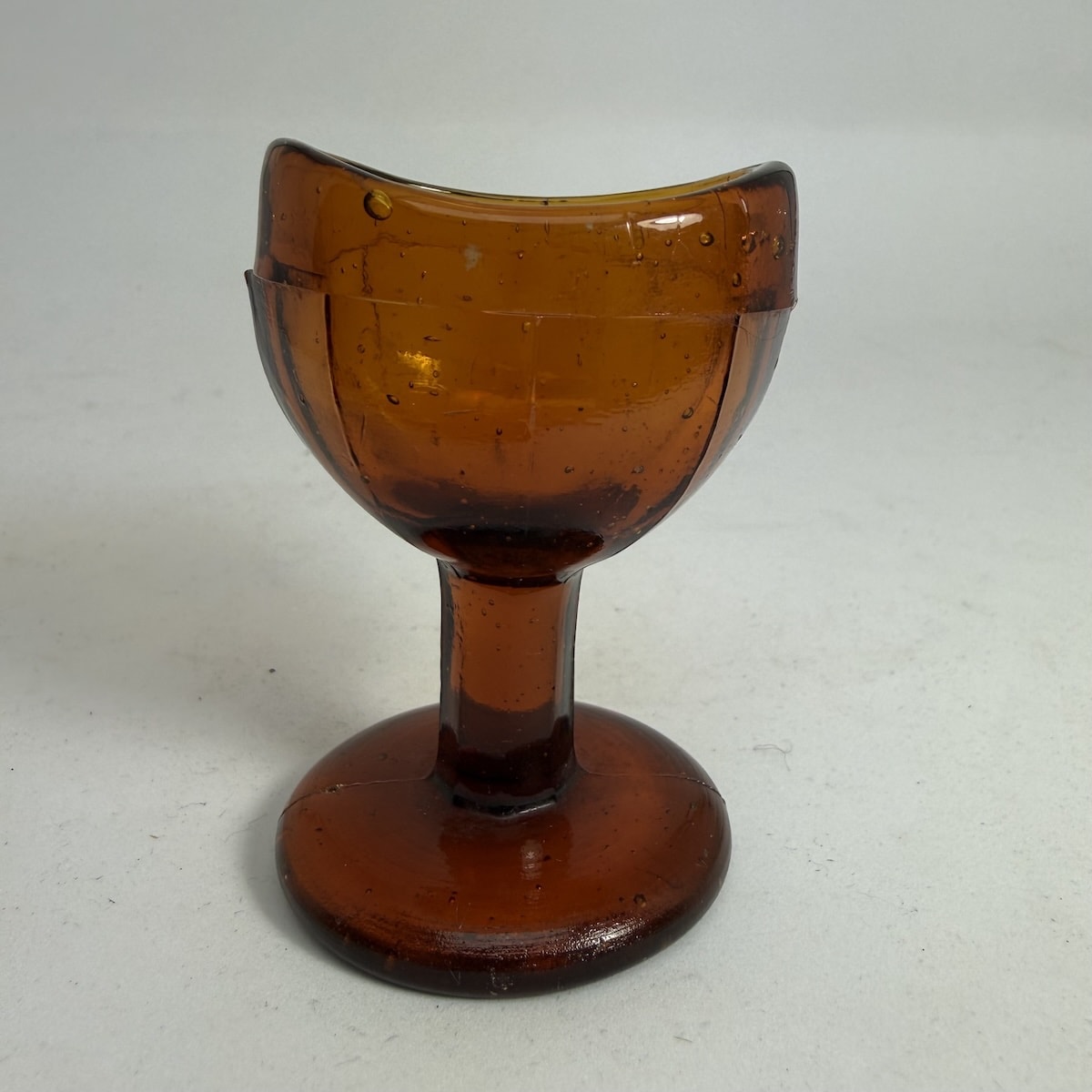 Eye Bath. Amber Glass, Rich anber colour. Pedestal. Facetted Bowl. No markings.