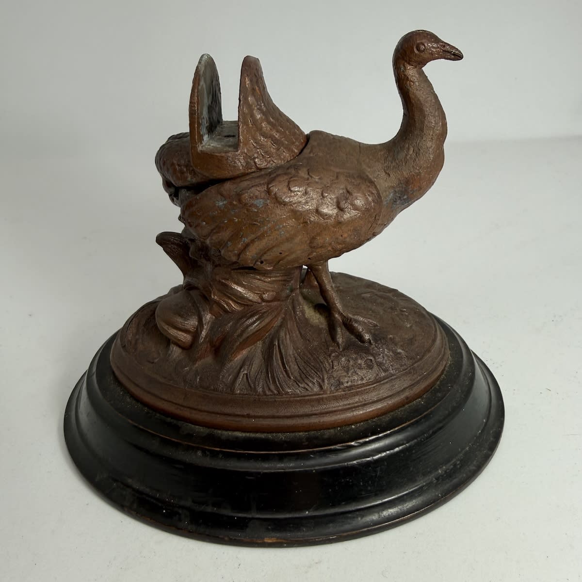 Inkwell. Cast figure of a bird on a wooden base. Back has a holder and flips up to reveal a glass inkwell which is pontil scarred.