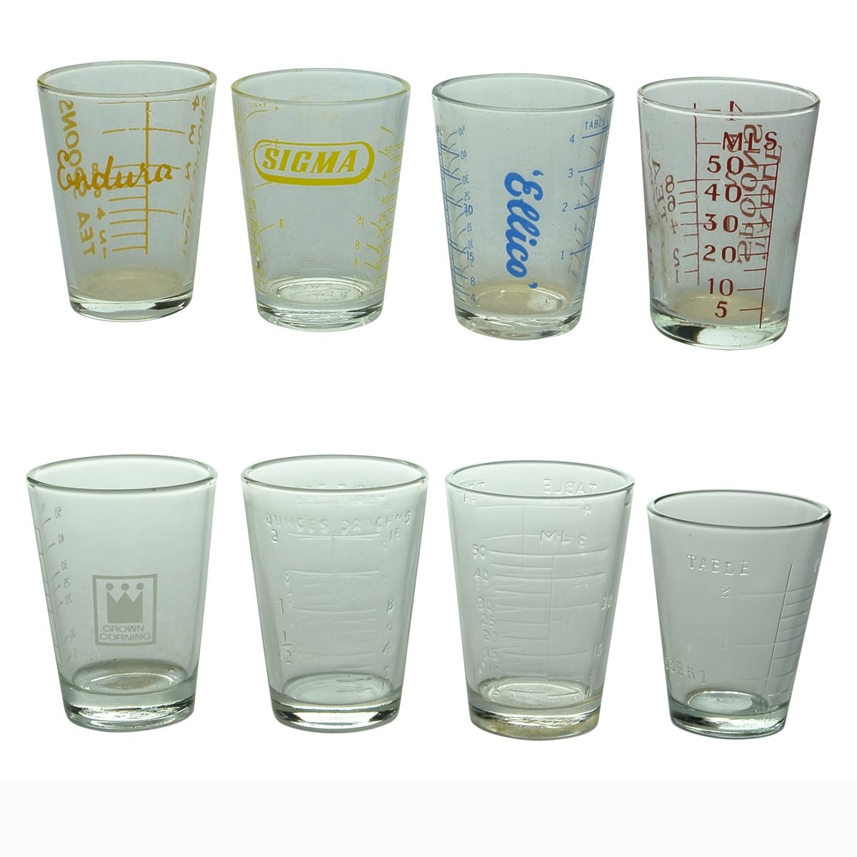 Glasses. Eight measuring glasses: 1. Endura. 2. Sigma. 3. Ellico. 4. Generic with red print up to 50 mls, 4 Tablespoons. 5. Crown Corning. 6. Graduated to 2 oz. 7. Graduated to 50 mL. 8. Graduated to 2 Tablespoons.
