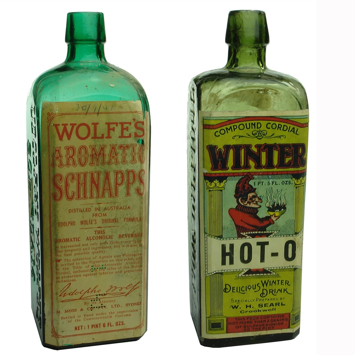 2 Udolpho Wolfes Schnapps with Labels: Later one with original label dated 1941; Early bottle with later W. H. Searl Crookwell Winter Hot-O Cordial Label.