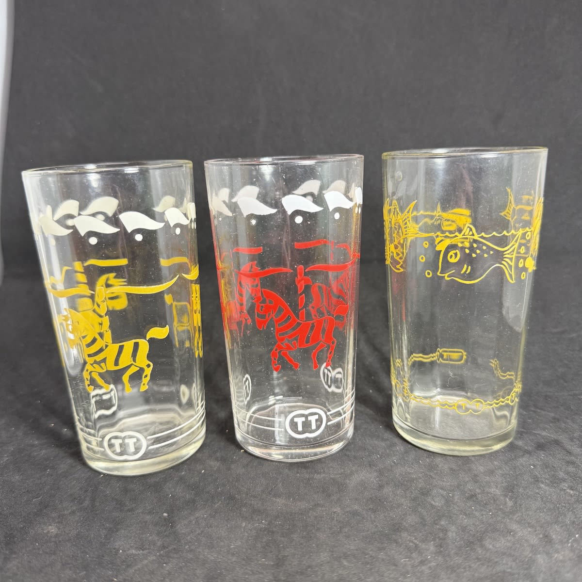 3 Advertising Novelty Glasses. 2 x Carousel, Circus, Zebra decoration (Yellow & White and Red & White) Fish Decoration (Yellow). T. Tristram, Brisbane. (Queensland)
