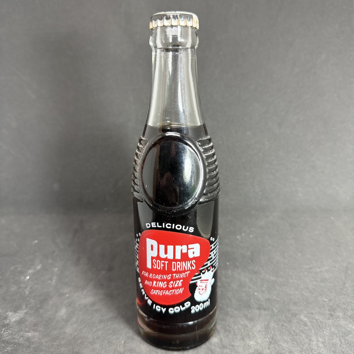 Ceramic Label Crown Seal. Pura Cordials Pty. Ltd. Old Dookie Rd, Shepparton. Pura Soft Drinks. Generic Sarsaparilla Cap and contents. 200 ml. "Bullet" shape bottle. (Victoria)