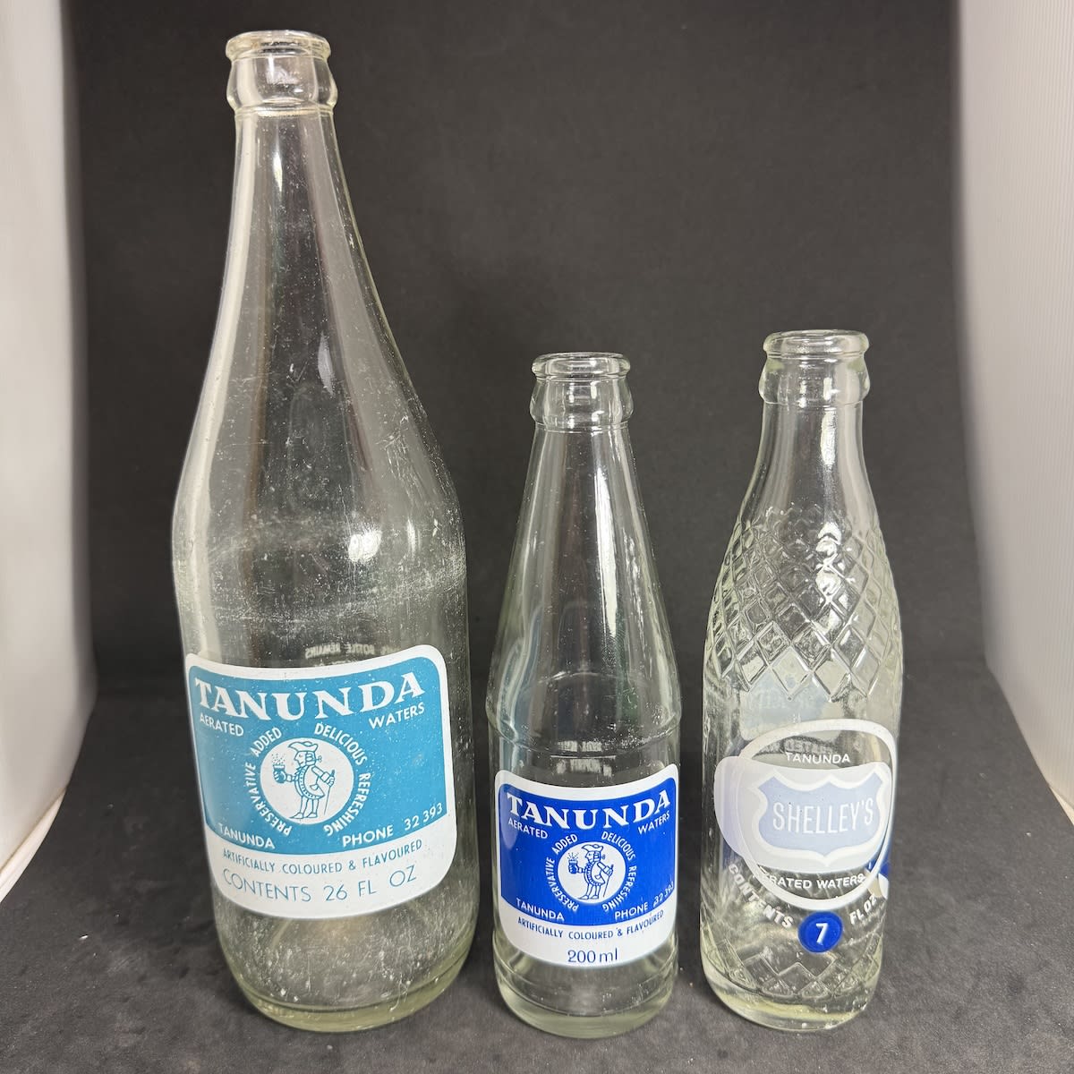 3 Tanunda Aerated Waters Ceramic Label Crown Seals: 26 oz 200 ml 7 oz with Tanunda Aerated Waters in white over the top of a Shelley's Sydney bottle. (South Australia)
